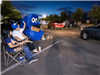 Two people wave at line of cars with cookie monster decorations