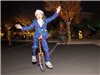 Girl on a unicycle looking happy and excited in a Christmas printed suit