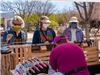 Three women in masks looking at booth