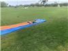 Teen sliding on their belly at the end of a slipnslide