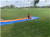Teen sliding on their knees at the end of a slipnslide